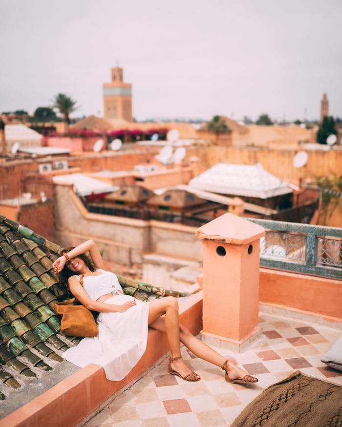 hero-gallery-01 Woman relaxing on a rooftop in Marrakesh, Morocco, capturing the vibrant urban skyline and warm tones of the city.