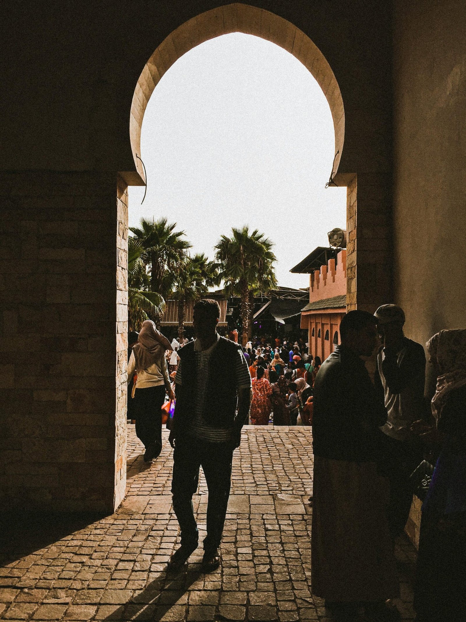 Silhouetted people walking through an archway in Agadir, Morocco bustling with urban life.